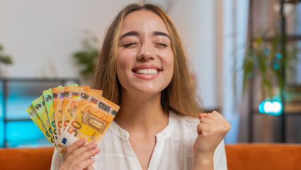 Lachende vrouw heeft bankbiljetten van 50 en 100 euro in haar hand.