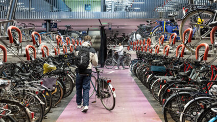 Iemand parkeert zijn fiets tussen de andere fietsen op het station