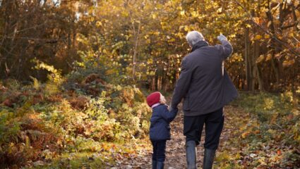 Een kind met haar opa in het bos in de herfstvakantie.