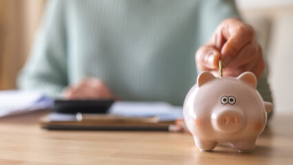 Mevrouw stopt geld in een spaarpot.