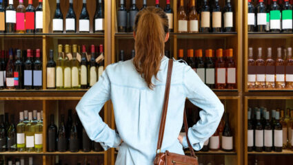 Vrouw kijkt op voedingsetiket van een fles wijn.