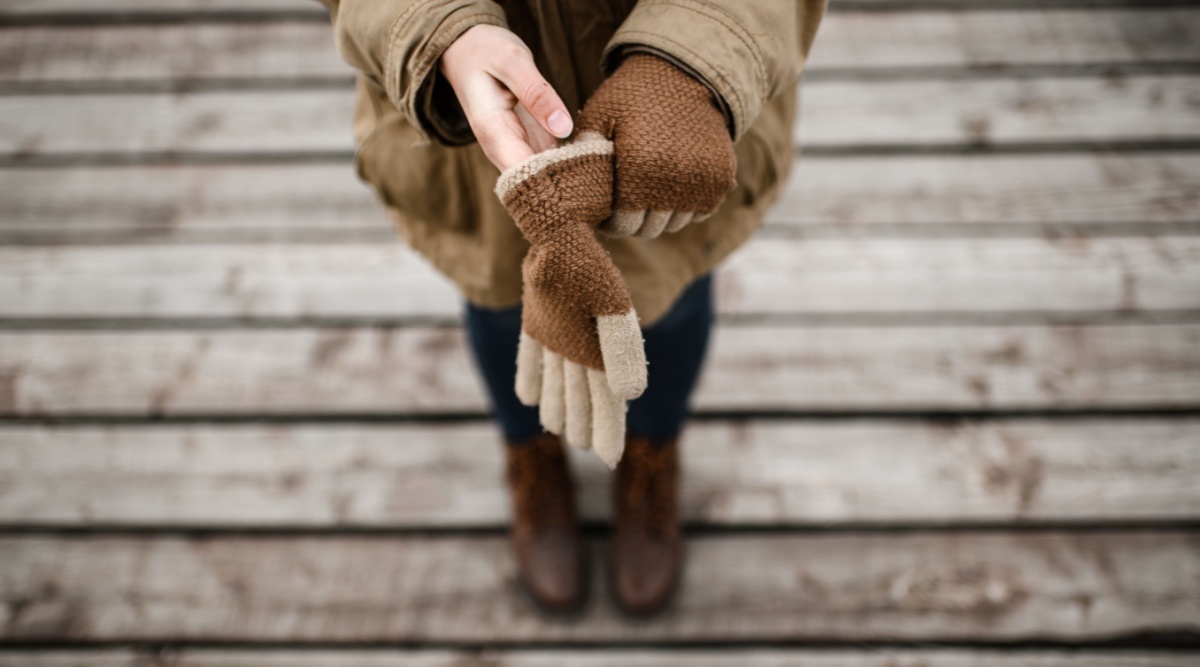 Een vrouw trekt handschoenen aan.