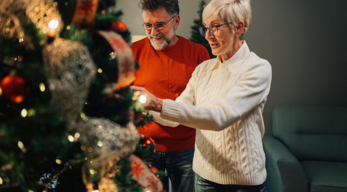 Een man en vrouw versieren de kerstboom.