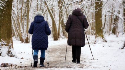 Twee vrouwen lopen in het bos in de winter om in beweging te blijven.