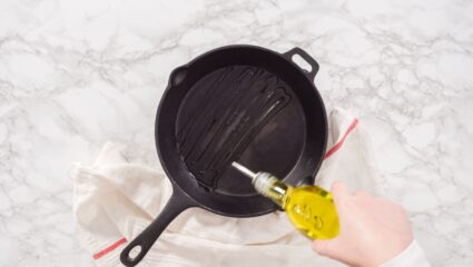 Een gietijzeren pan die wordt ingesmeerd met olie