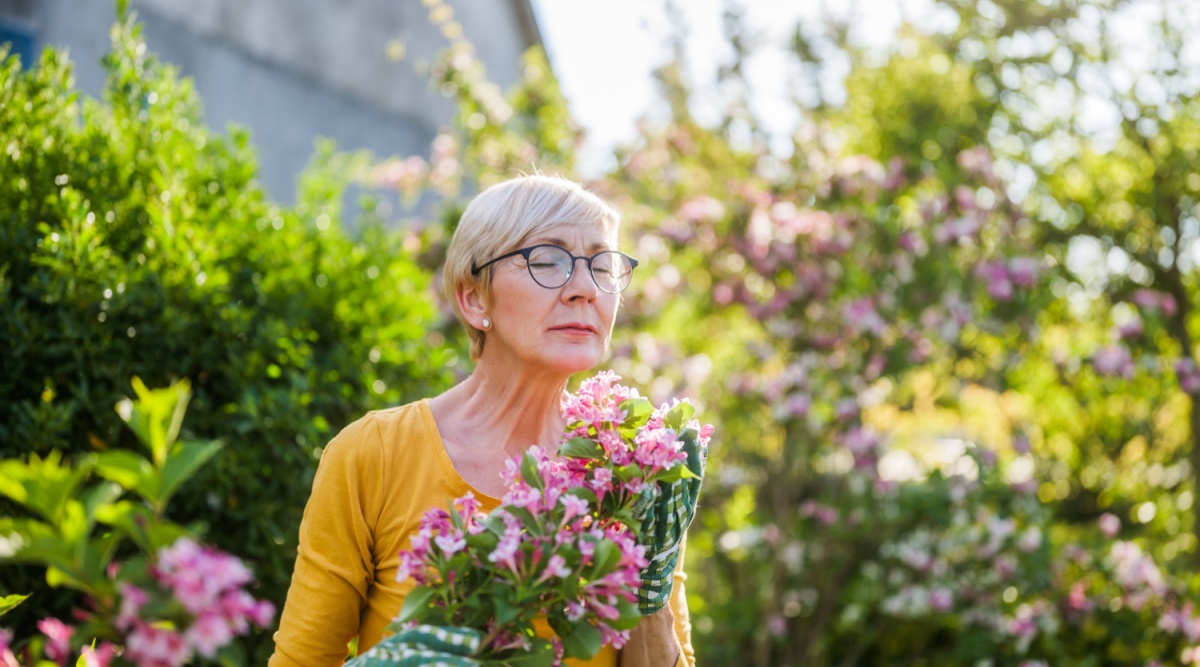 Een vrouw ruikt aan een bos bloemen.