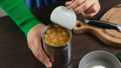 Een vrouw opent een blik bonen in vocht