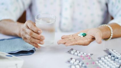 Een vrouw neemt supplementen in met een glas water in haar hand