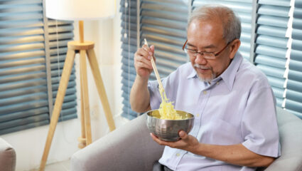 Meneer eet in een stoel.