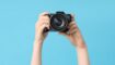 Handen met fotocamera en blauwe achtergrond