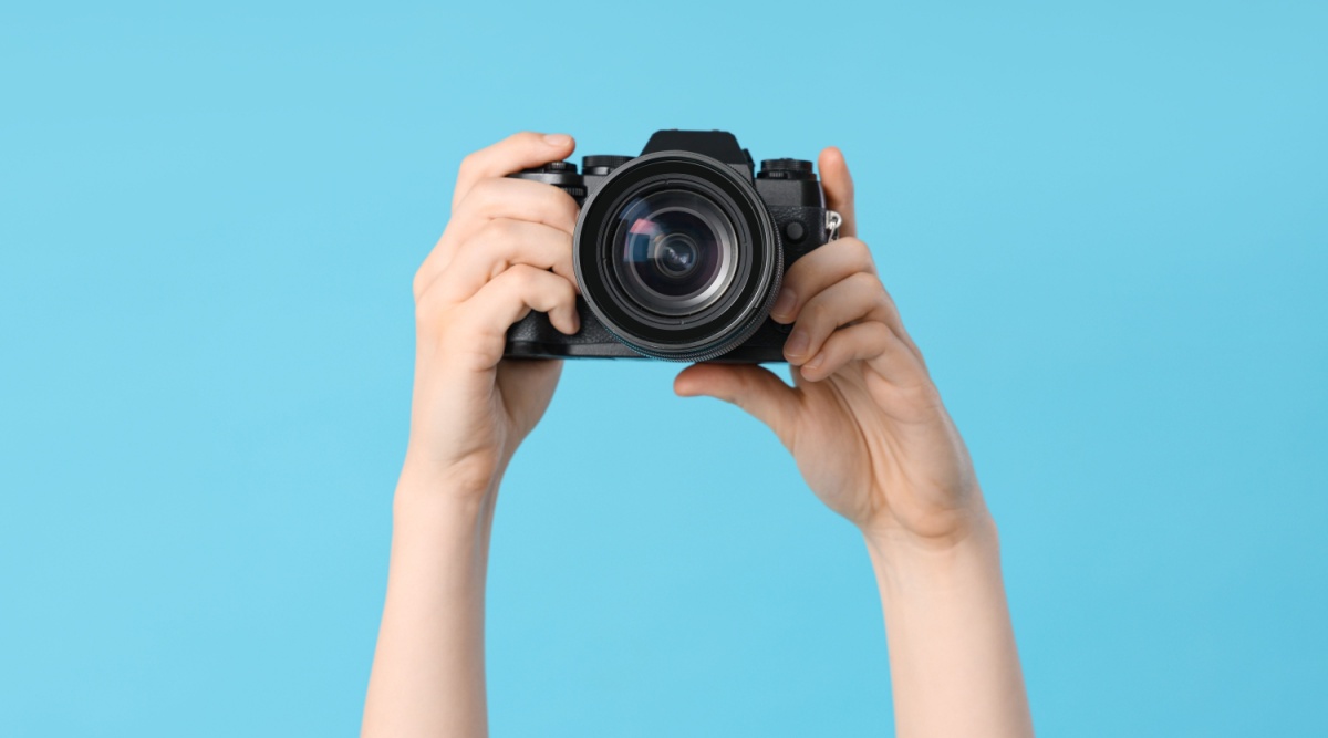 Handen met fotocamera en blauwe achtergrond