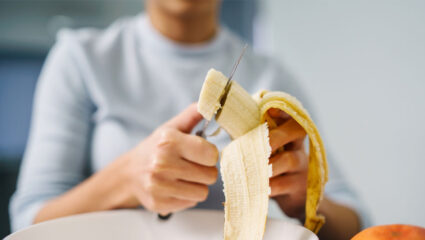 Een vrouw eet een banaan