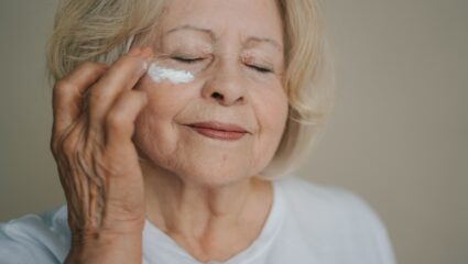 Een vrouw doet gezichtscrème op haar gezicht.