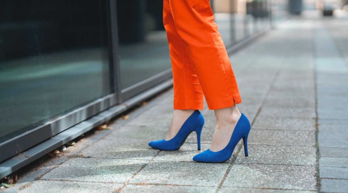 Persoon in oranje broek op blauwe hoge hakken op straat