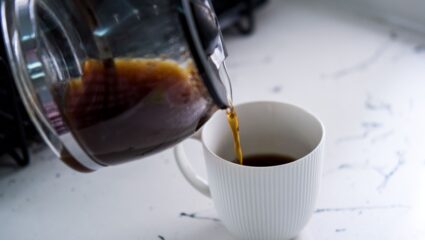 Zwarte koffie uit koffiepot in een wit kopje