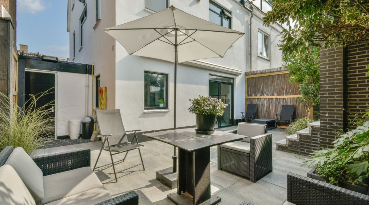 Parasol in tuin met tafel en stoelen