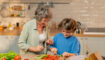Oma en kleinkind koken samen in de keuken.