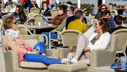 Een groep mensen, die in de zon geniet van terrasweer