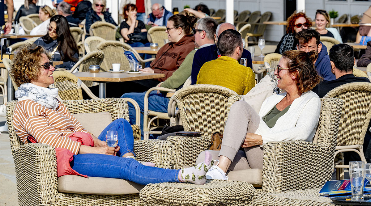 Een groep mensen, die in de zon geniet van terrasweer