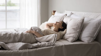 Een vrouw ligt in bed te slapen onder een deken.