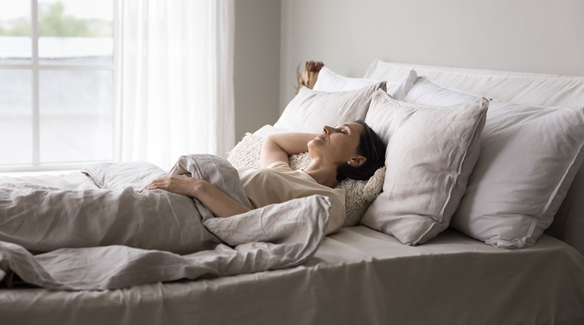 Een vrouw ligt in bed te slapen onder een deken.