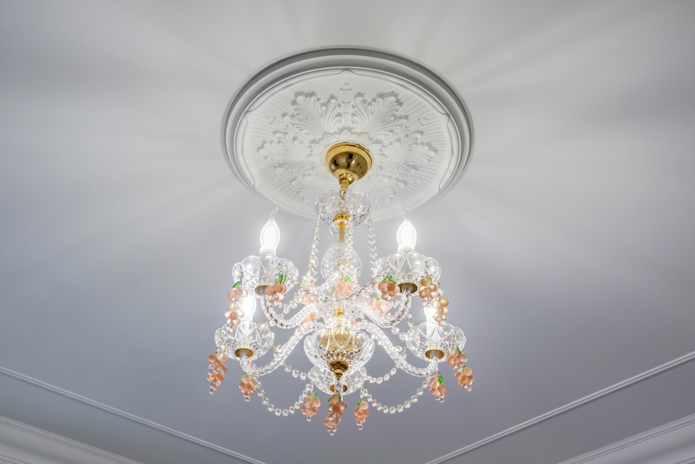 Een gipsornament op het plafond met een kroonluchter